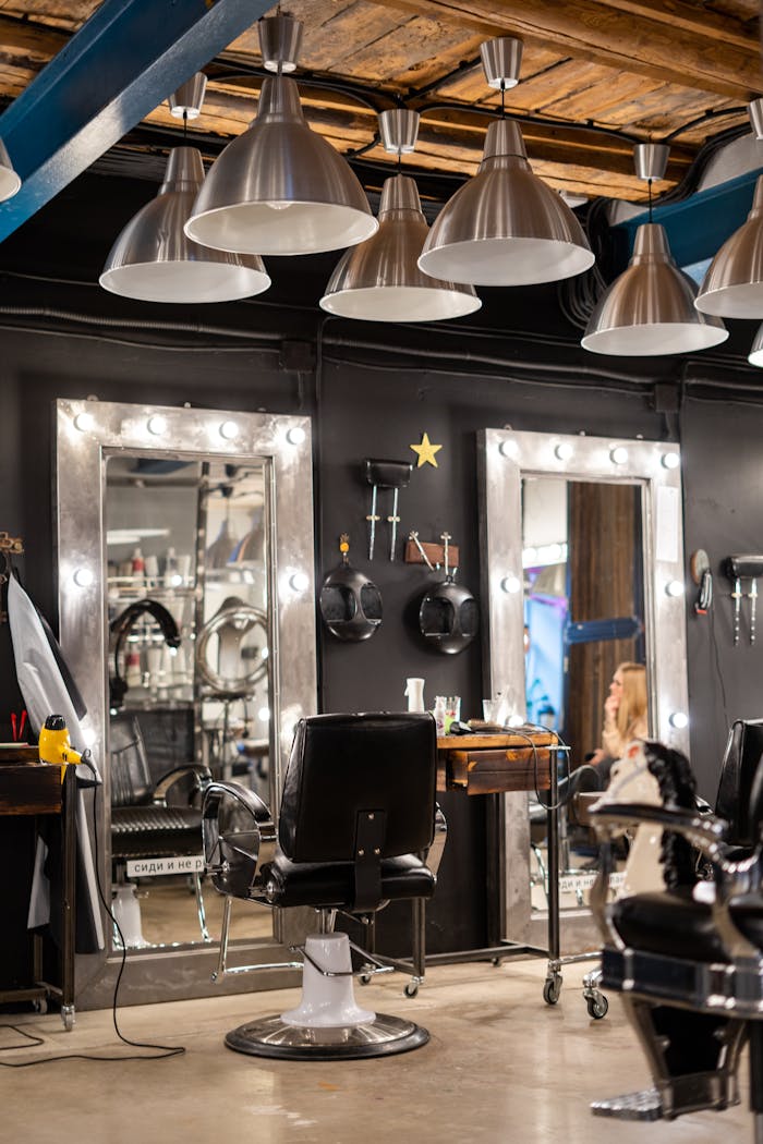 Cozy and stylish hair salon interior featuring chairs and illuminated mirrors.