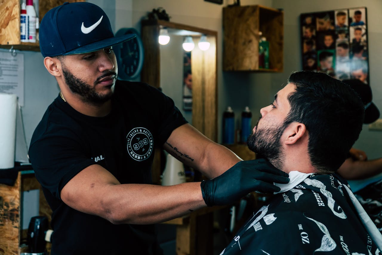 Barber trimming a client's beard in a stylish barbershop setting.